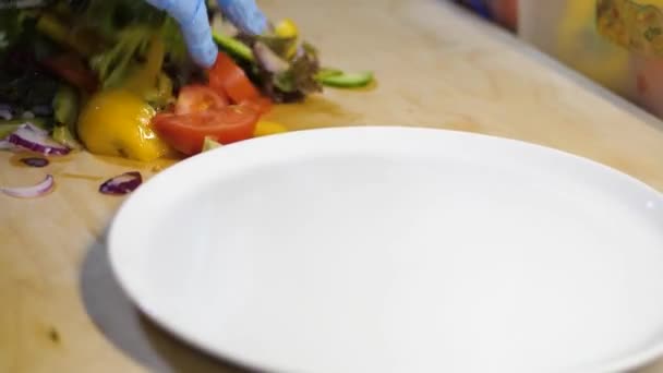 Adam sebzeleri karıştırıyor ve beyaz tabağa salata koyuyor. — Stok video