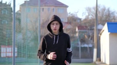 Kapüşonlu genç bir adam antrenmandan önce ısınıyor. fitness