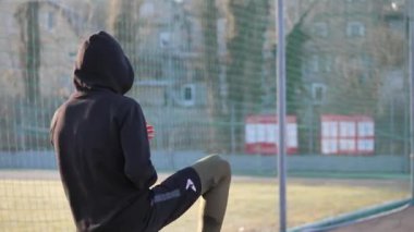Kapüşonlu genç bir adam antrenmandan önce ısınıyor. fitness