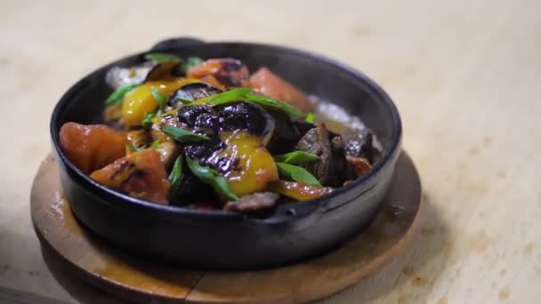 Κοντινό πλάνο. Ο σεφ βάζει το έτοιμο ζεστό πιάτο σε ένα τηγάνι από χυτοσίδηρο. τηγανητά λαχανικά — Αρχείο Βίντεο
