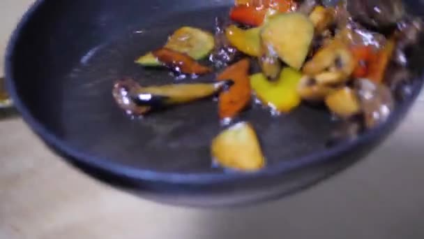 Крупным планом. Шеф-повар жарит овощи на сковороде. разноцветные овощи выбрасывая их — стоковое видео