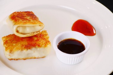 Beyaz tabağa doldurulmuş krep ve sos. Siyah arka plan. Görünüm