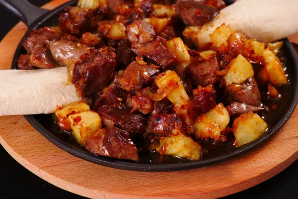 Kızartma tavasında yağlı et parçaları. Kavurma. Pita. Siyah arkaplan