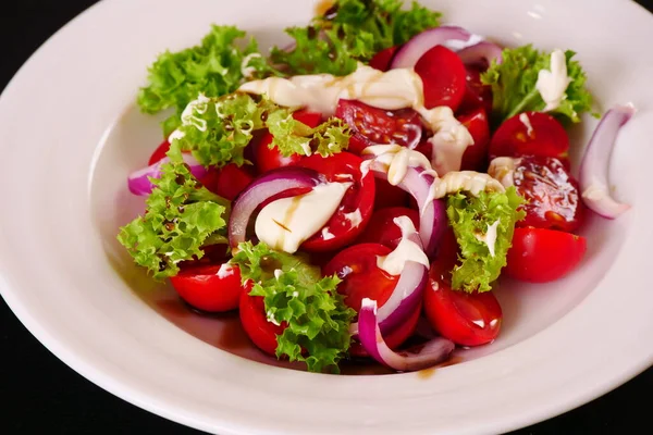 Soğanlı ve ekşi kremalı domates salatası. Marul yaprakları. Siyah arkaplan — Stok fotoğraf