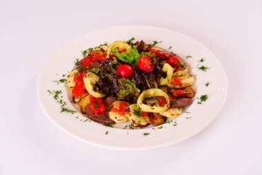 Izgara et ve sebze, dilimlenmiş, domates ve marul yapraklarıyla süslenmiş.