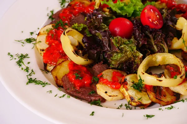 Mięso i warzywa z grilla, krojone, ozdobione pomidorami i liśćmi sałaty — Zdjęcie stockowe