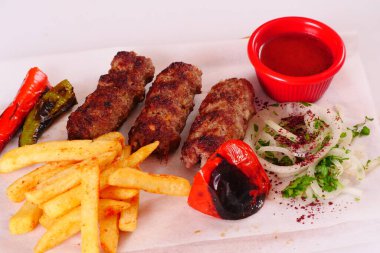 Doğranmış et, biber, domates, patates kızartması, ahşap bir tahtanın üstünde soğan.