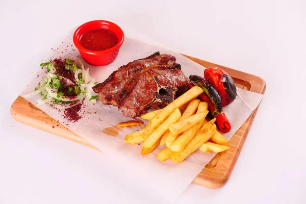 Kızarmış et, biber, domates, patates kızartması, sos, tahta üzerinde soğan.