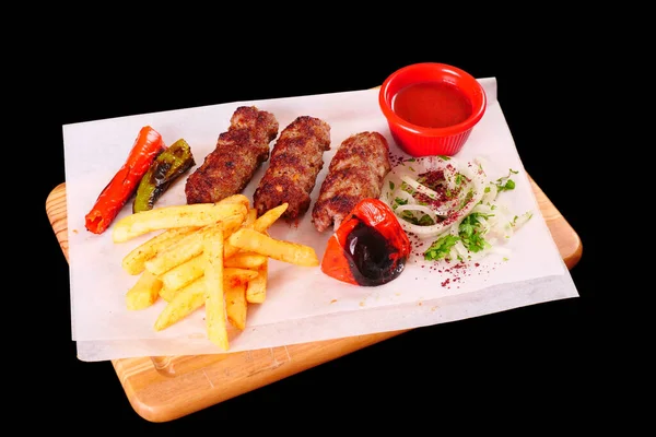 Doğranmış et, biber, domates, patates kızartması, ahşap bir tahtanın üstünde soğan.