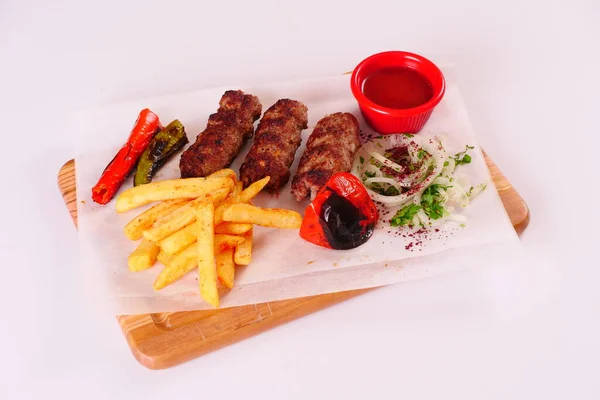 Doğranmış et, biber, domates, patates kızartması, ahşap bir tahtanın üstünde soğan.