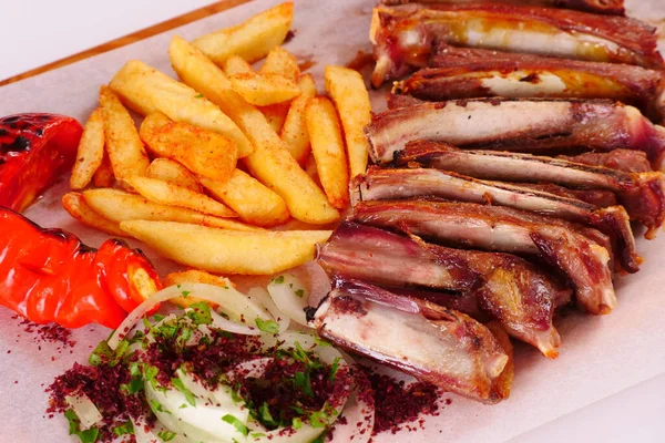 Izgarada kaburga, biber, domates, patates kızartması, tahtadan soğan