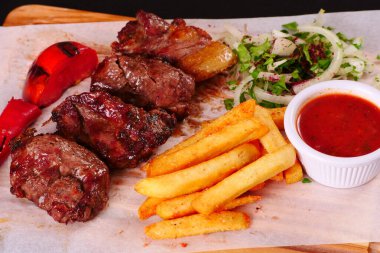 Kebap, biber, domates, patates kızartması, tahtadan yapılmış soğan. Siyah arkaplan
