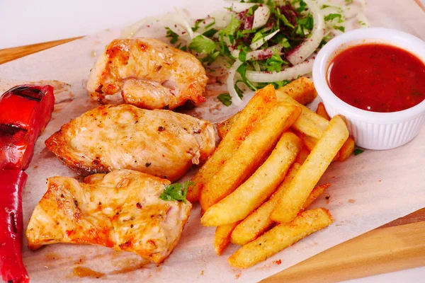 Grilled chicken fillet, chili, tomato French fries ketchup onion on wooden Board