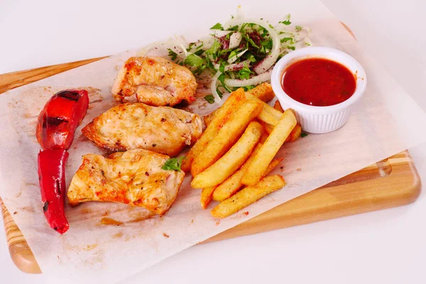 Grilled chicken fillet, chili, tomato French fries ketchup onion on wooden Board