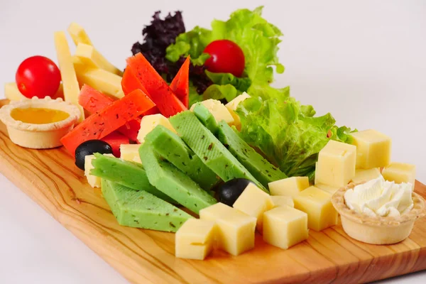 Cheese platter, red and green pesto cheese, lettuce tomatoes on the wooden board — Stock Photo, Image