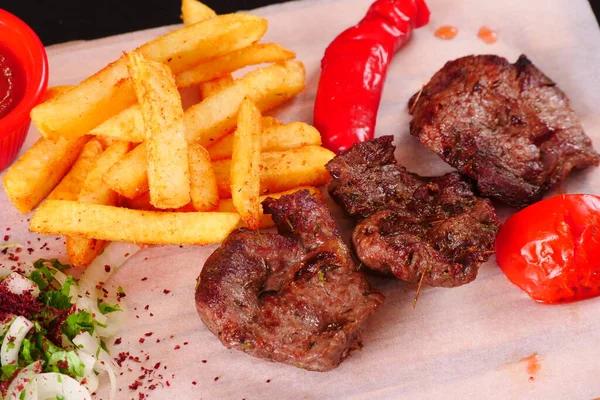 Kebap, biber, domates, patates kızartması, tahtadan yapılmış soğan. Siyah arkaplan