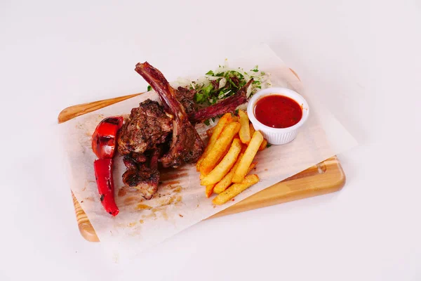 Izgara kuzu pirzolası, biber, domates, patates kızartması, ahşap tahtada ketçap soğan