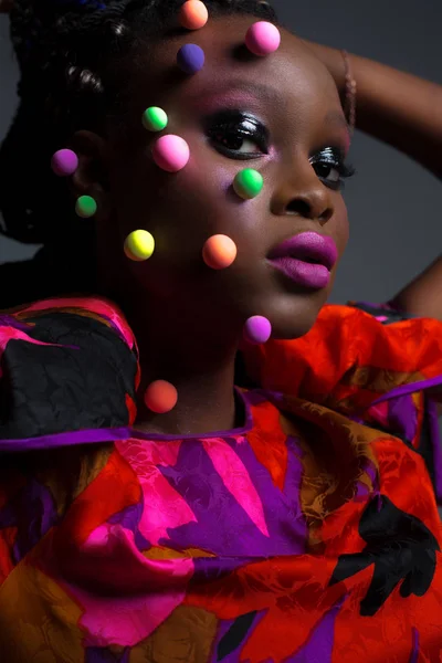 Művészeti portré fényes ruhában szürke háttérrel a stúdióban. Közelkép szépség portré afrikai nő kreatív smink stúdióban. — Stock Fotó