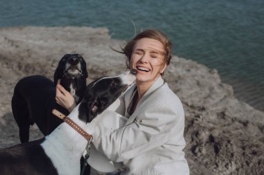 Bir kadın köpeklerle yürürken gülüyor. Köpekli, beyaz şapkalı, gülümseyen kadın portresi. .