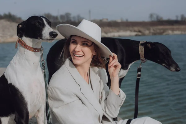 Woman laughing on walk with dogs . Portrait of smiling woman in white hat with dogs .