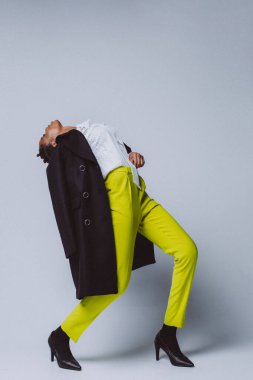 Parlak elbiseli esmer model beyaz arka plana basıyor. Beyaz arka planda, stüdyo ortamında tam gelişim gösteren şık giyinen Afrikalı kadın.