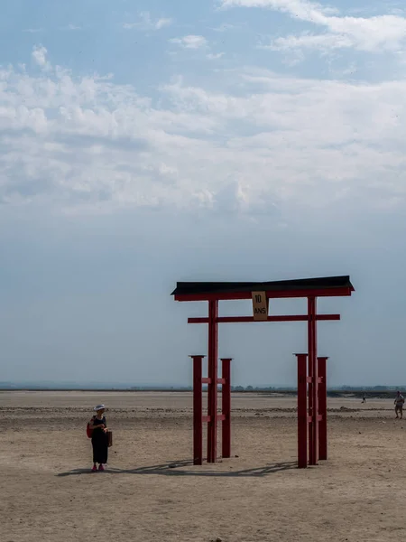 MONT SAINT-MICHEL, FRANCE, July, 25, 2019 : Asian woman in the shadow of the the  Japanese Torii in the bay of Mont Saint-Michel commemorates help of Japan in renewing the bay.