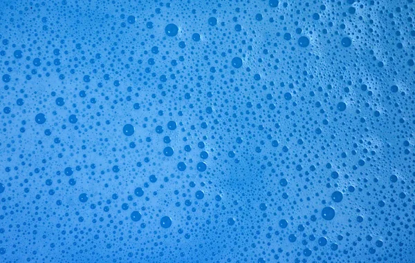 Espuma transparente sobre fondo de agua azul. La textura de la — Foto de Stock