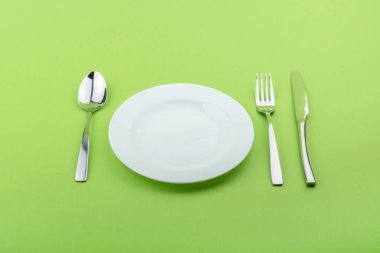 boş tabak, çatal ve bıçak yeşil zemin üzerine