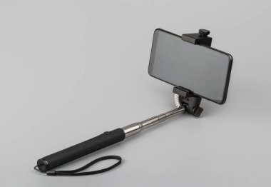 Gri arkaplanda telefon olan selfie çubuğu