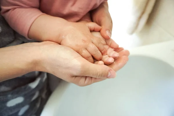 Mother helping her kid washing hands with water and liquid soap - Teaching baby clean and healthy manners against bacteria - Personal hygiene