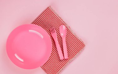 Pink color plastic plate with plastic spoon, fork and cloth napk