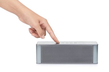 Hand pressing the on-off button of Wireless speaker for listenin