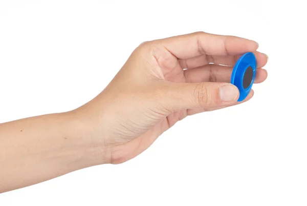 Рука держит синий круглый пластиковый магнит изолирован на белой backgro — стоковое фото