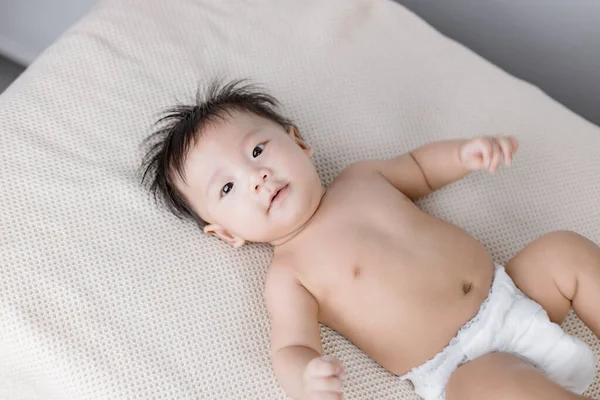 Baby boy lying on bed in bedroom — Stock Photo, Image