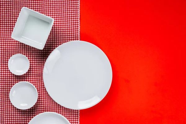 white Kitchenware set with tablecloth on red background