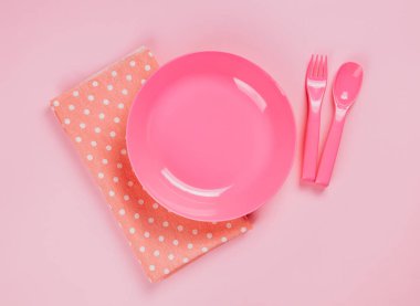 Pink color plastic plate with plastic spoon, fork and pink polka