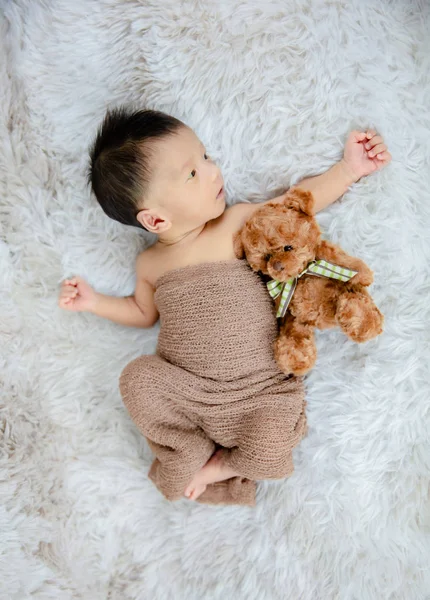 Pequeno bebê deitado abraçando um ursinho de pelúcia. — Fotografia de Stock