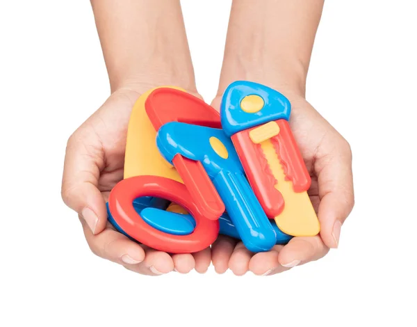 Mão segurando ferramentas de conjunto de brinquedo de plástico isolado no backgrou branco — Fotografia de Stock