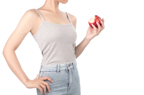 Femme en débardeur gris et jeans mangeant une pomme rouge isolé o — Photo