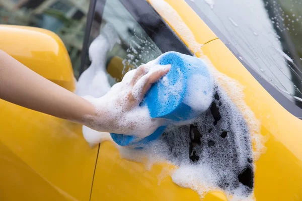 Close-up de mão com esponja azul lavando carro amarelo — Fotografia de Stock