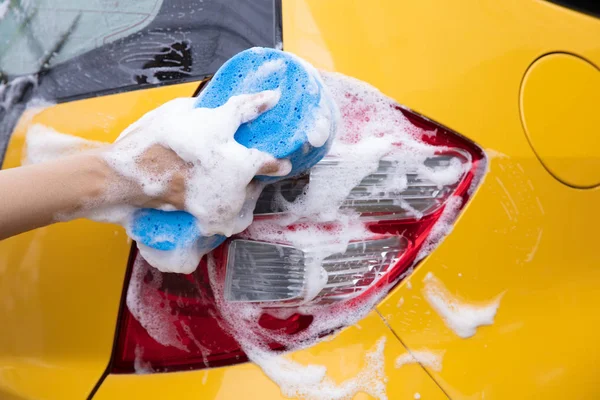 Primer plano de la mano con esponja lavado coche amarillo — Foto de Stock