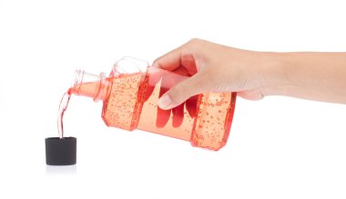 Hand pouring water mouthwash from bottle in to cap isolated on w