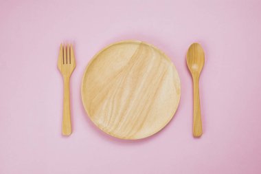 Pembe arka planda ahşap mutfak malzemeleri.