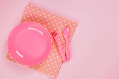 Pink color plastic plate with plastic spoon, fork and pink polka