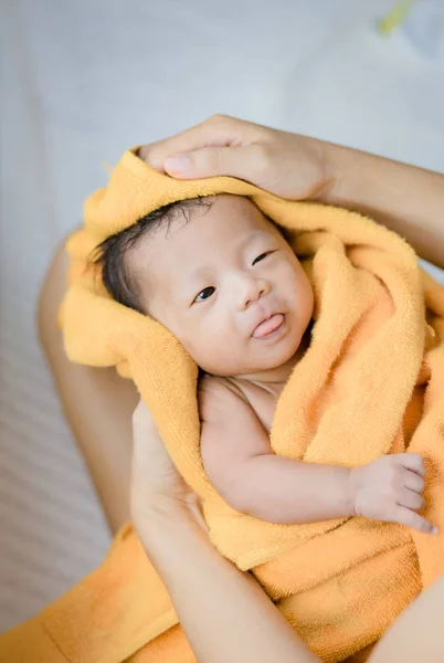 Μητέρα τρίψτε το σώμα στεγνό νεογέννητο μωρό με μια πορτοκαλί πετσέτα — Φωτογραφία Αρχείου