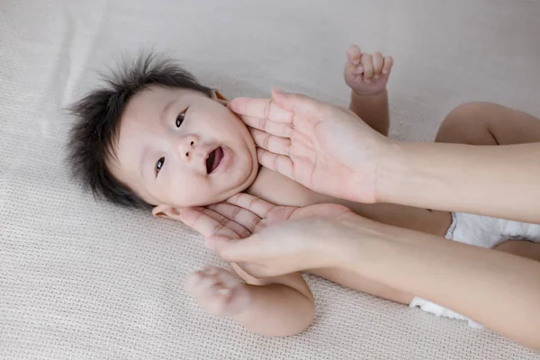 Mãe um bebê massageando na cama — Fotografia de Stock