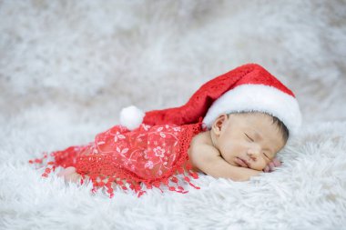 Kırmızı elbiseli bebek ve Noel Baba şapkalı.