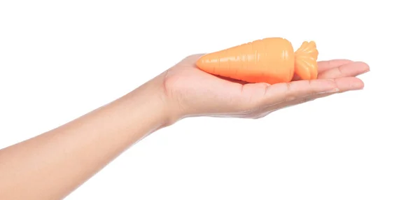 Hand holding plastic toy carrot  isolated on white background — Stockfoto