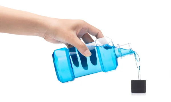 Mão derramando água enxaguante bucal do frasco para dentro para tampa isolada em w — Fotografia de Stock