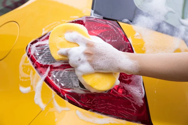 Primer plano de la mano con esponja lavado coche amarillo — Foto de Stock
